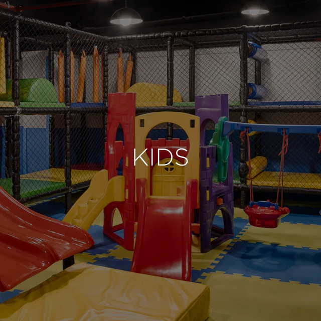 Parque infantil coberto com escorregadores, túneis e uma estrutura em forma de castelo; aparece o texto 