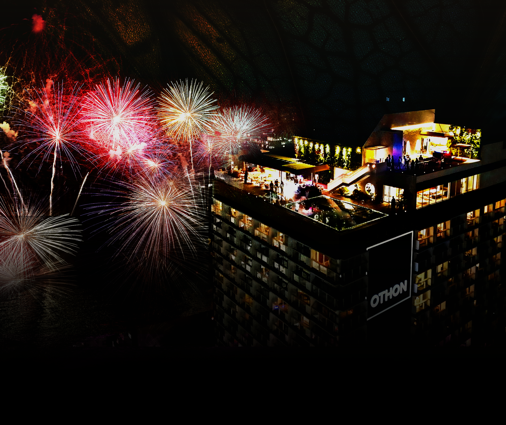 Fogos de artifício explodem sobre um bar e hotel iluminados na cobertura, à noite. Hotéis Othon