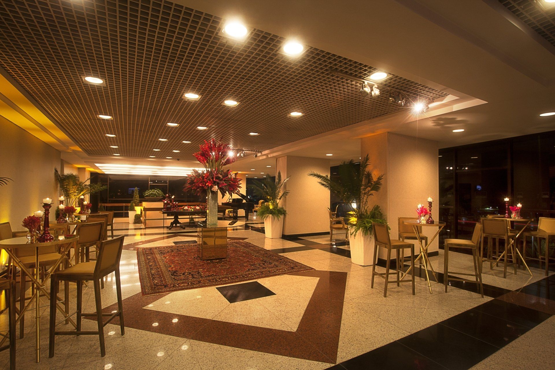 Um lobby de hotel com mesas e cadeiras e um vaso de flores