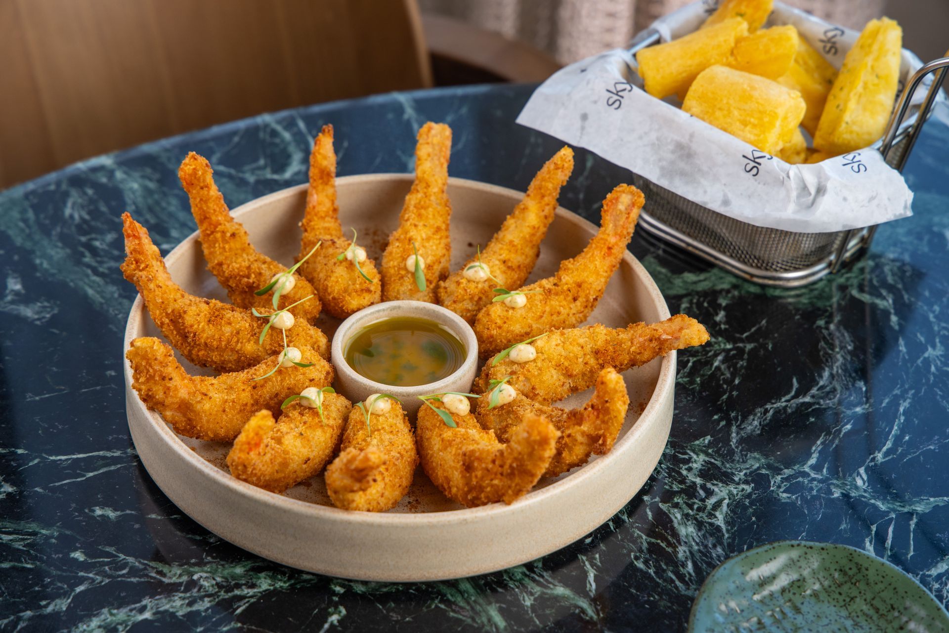 Prato de camarão empanado com molho e mandioca frita.