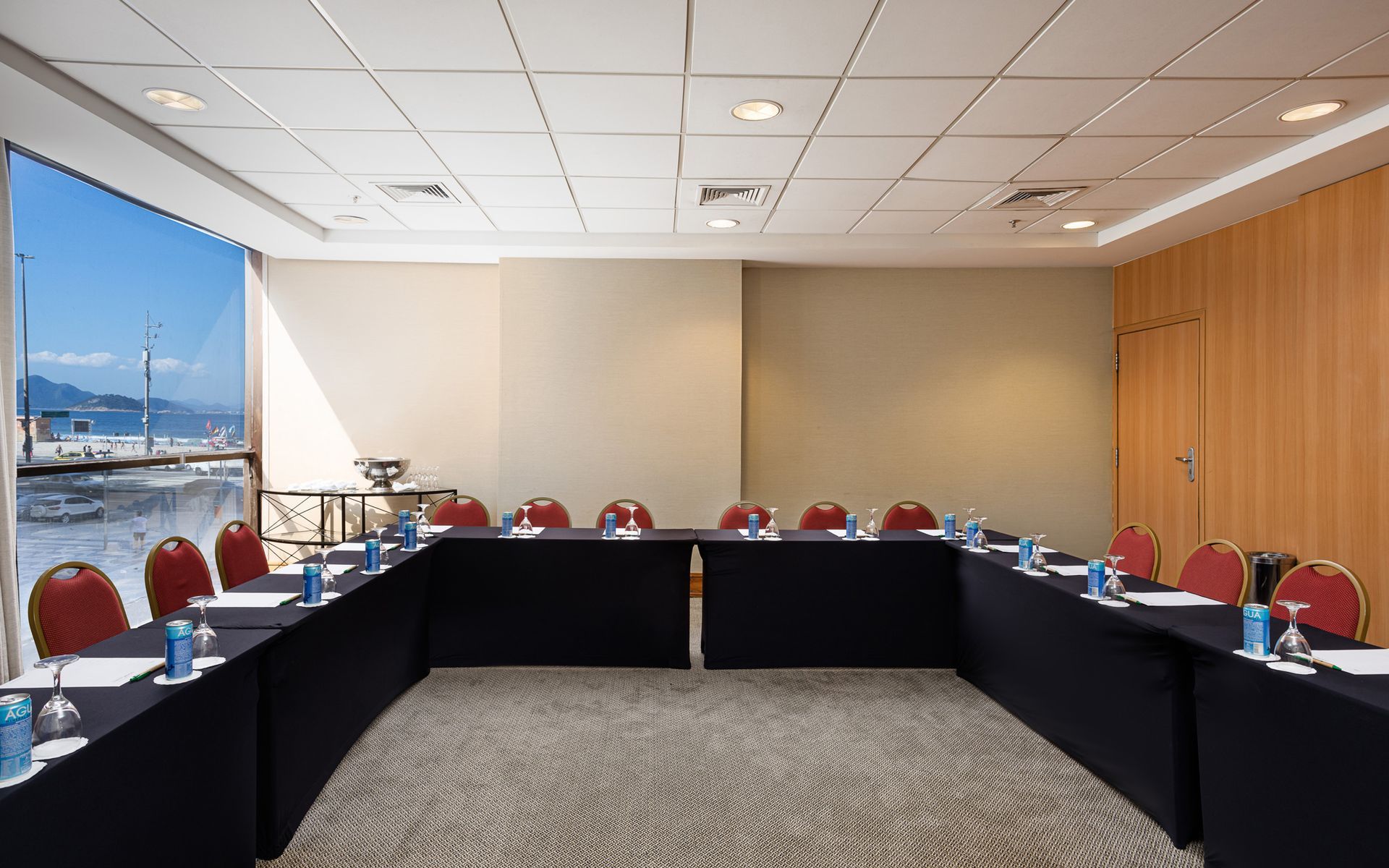 Uma sala de conferências com mesas e cadeiras longas preparadas para uma reunião.