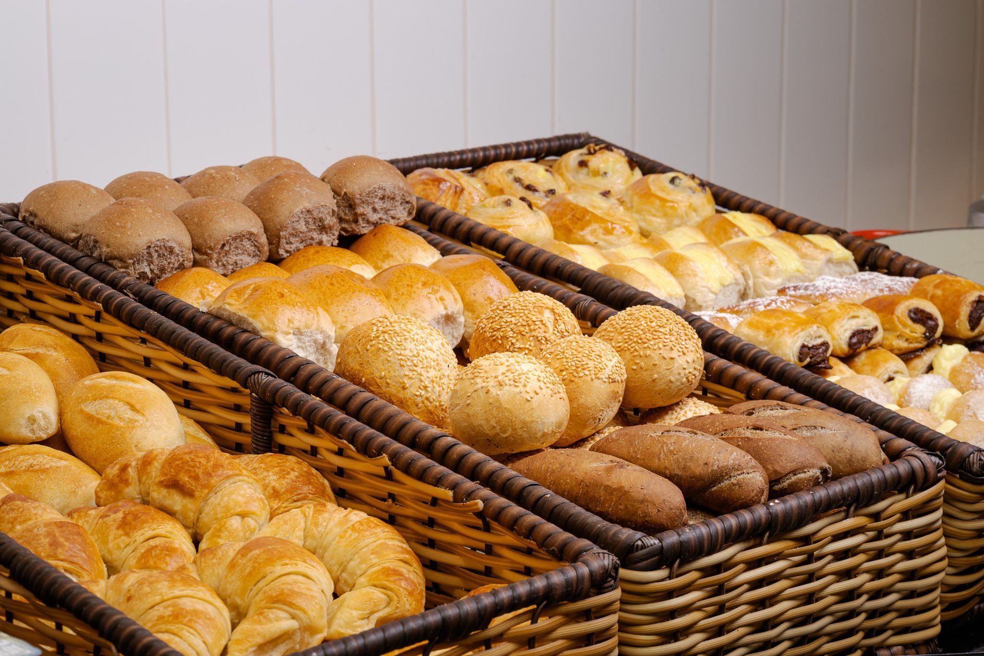 Cestas repletas de diversos produtos de panificação: croissants, pãezinhos, pão e doces.