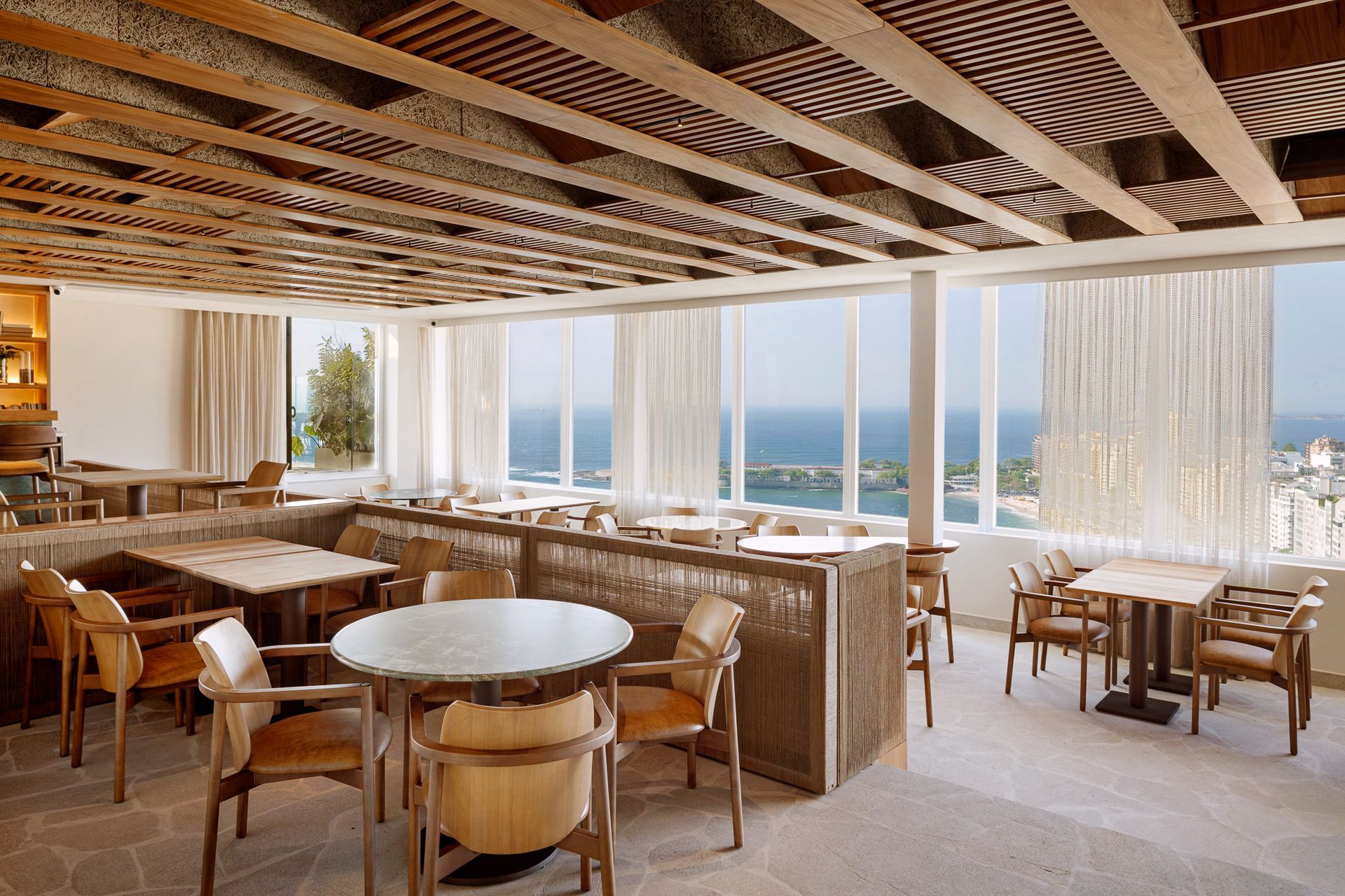 Um restaurante com mesas e cadeiras e vista para o oceano.