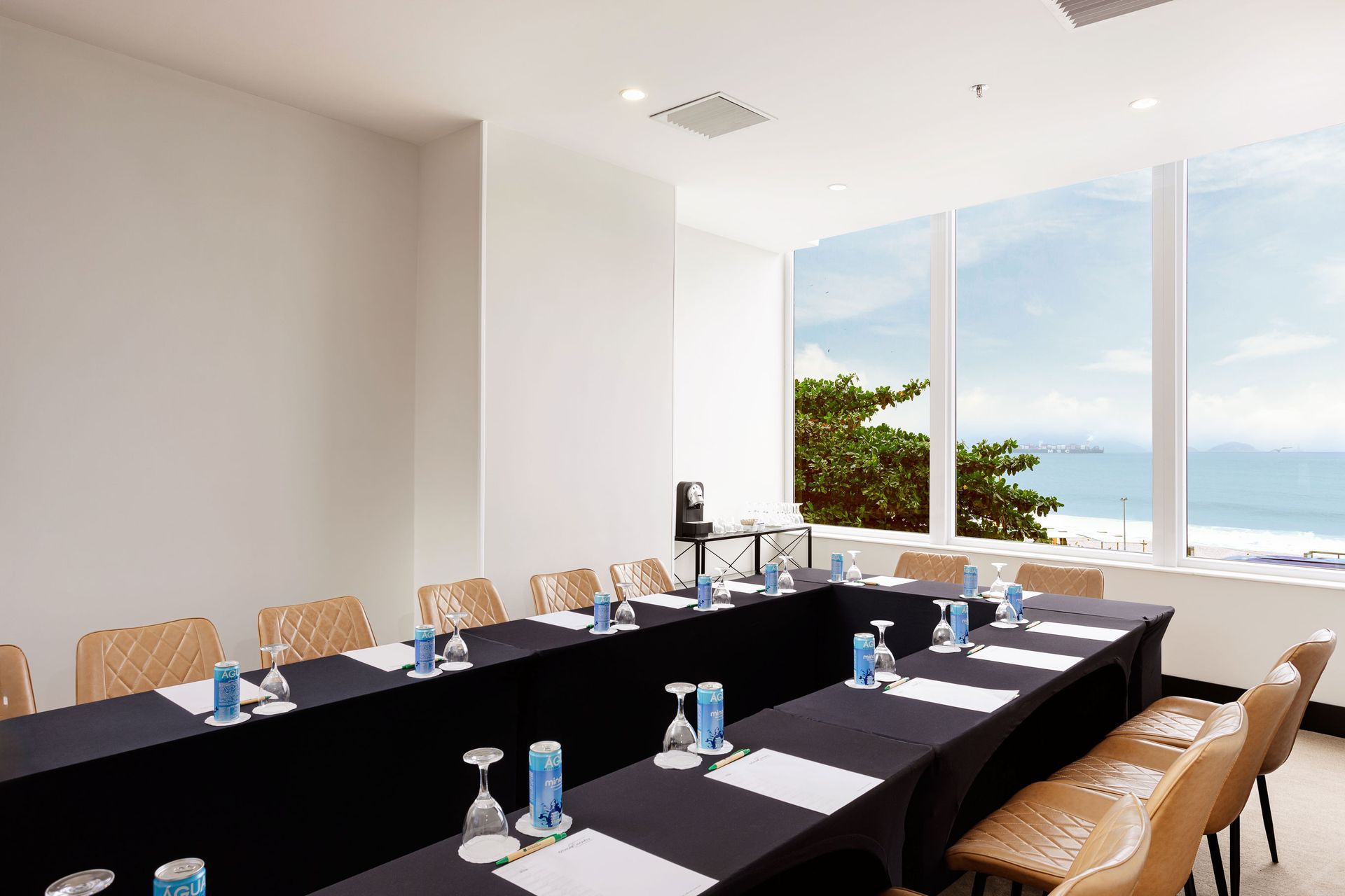 Uma sala de conferências com mesas e cadeiras e uma grande janela com vista para o oceano.