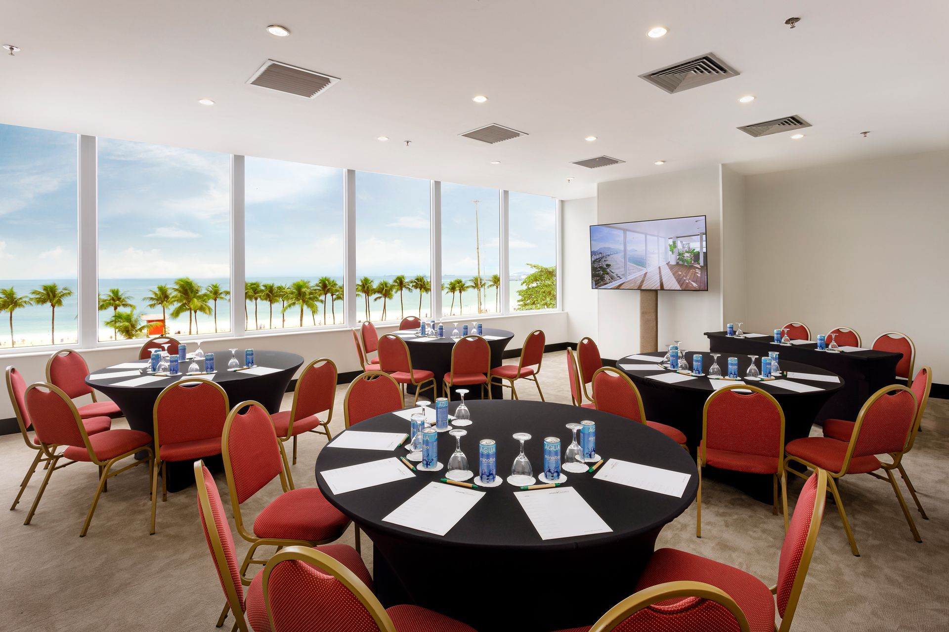 Uma sala de conferências com mesas redondas e cadeiras vermelhas