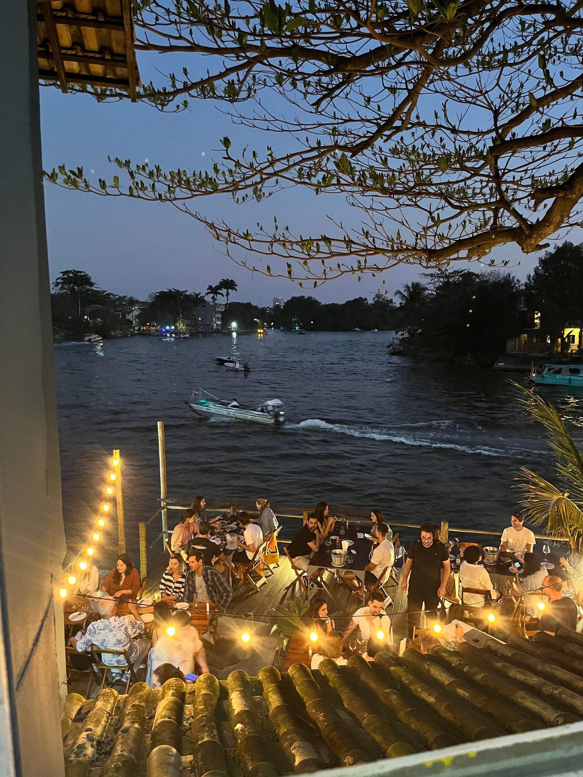 Um grupo de pessoas está sentado em um telhado com vista para um rio.
