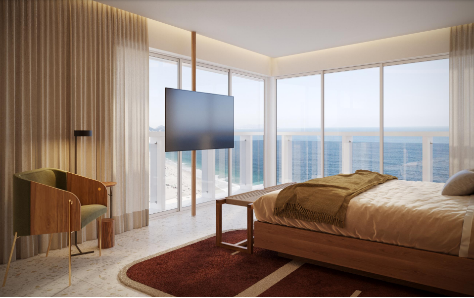 Um quarto com cama, cadeira, televisão e vista para o mar.