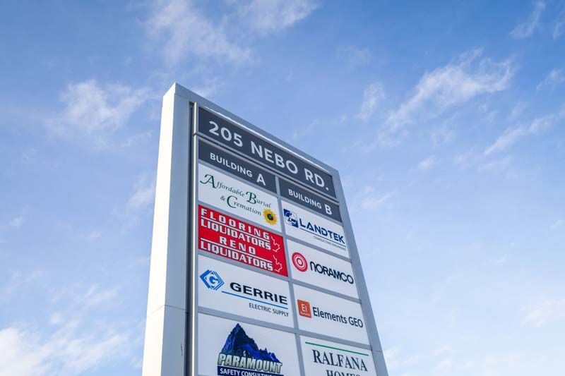 A sign for 205 nebo road is against a blue sky with clouds.
