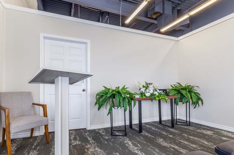 There is a podium in the middle of the room with plants on the tables.
