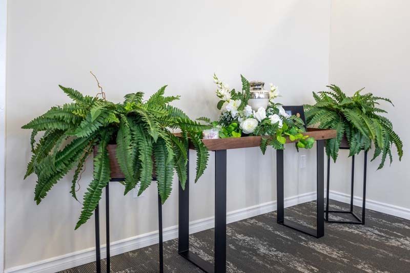 A table with ferns and flowers on it in a room.