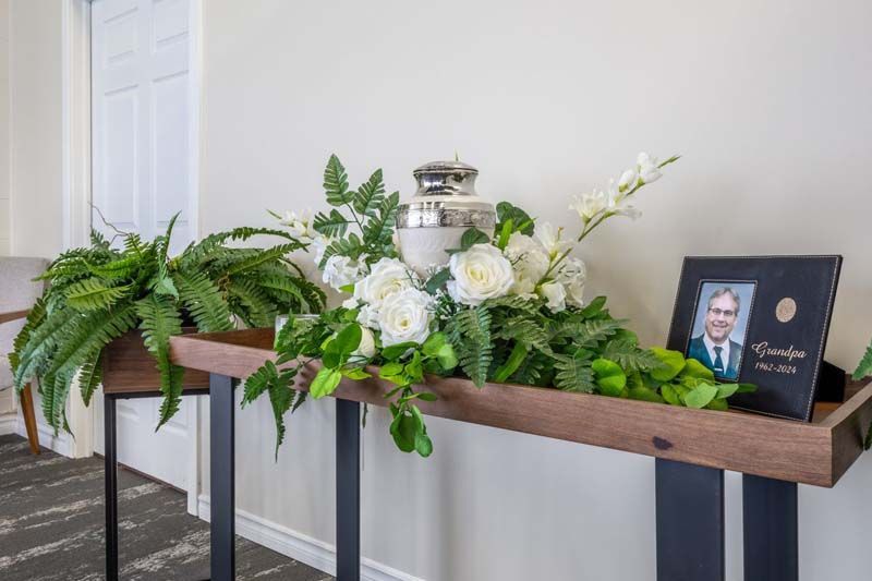 A wooden table with flowers and a picture of a man on it.