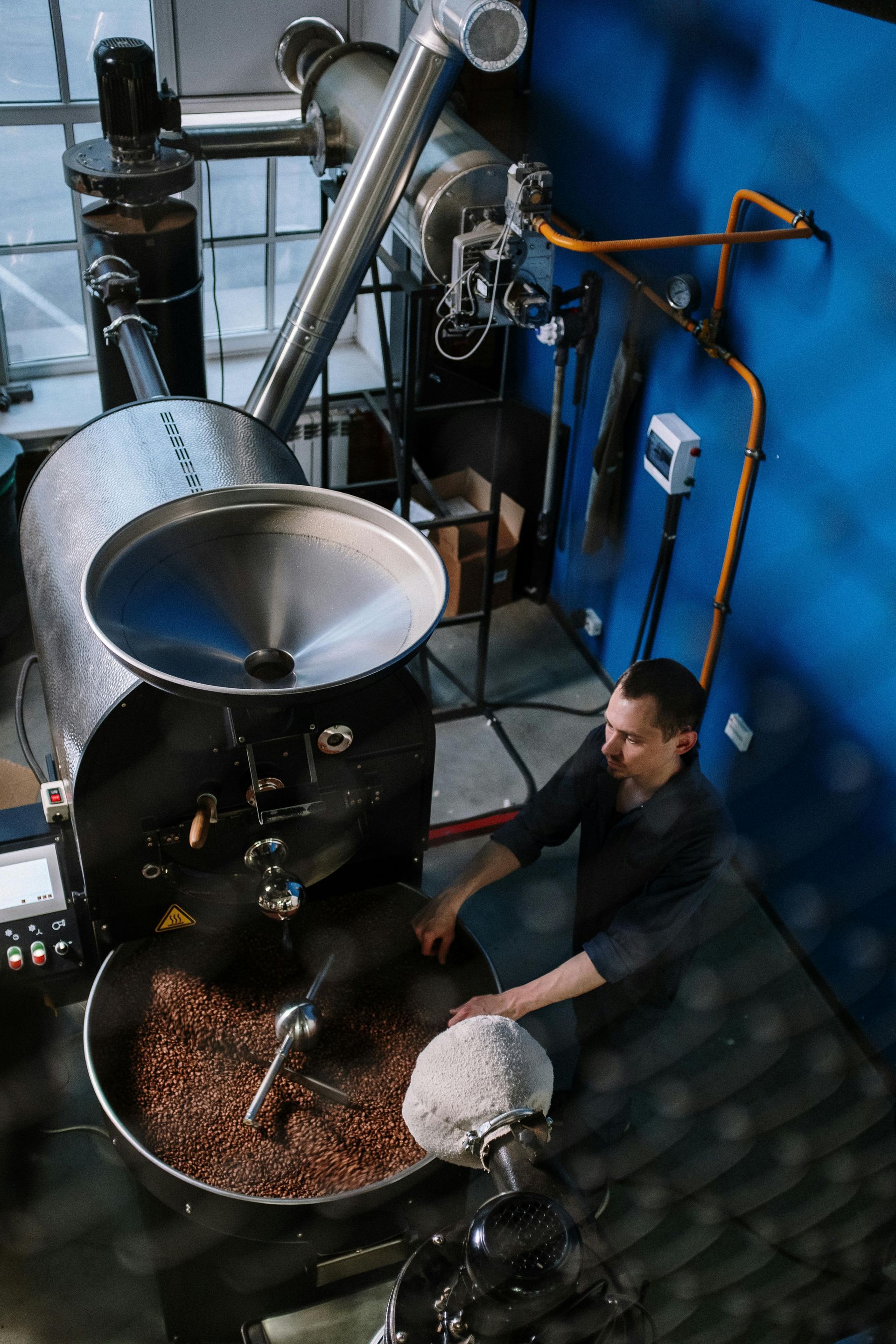 A man is roasting coffee beans in a machine.