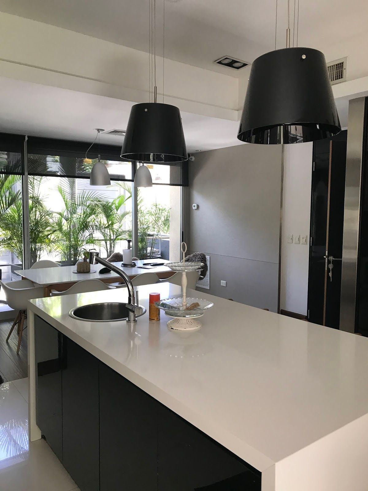 Una isla de cocina con encimera blanca y armarios negros, con dos lámparas colgantes negras suspendidas sobre ella.