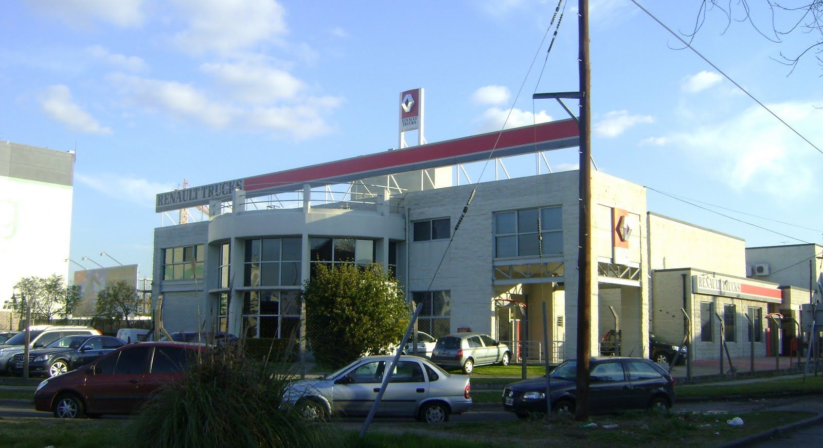 Un edificio comercial blanco de dos plantas con la marca en rojo