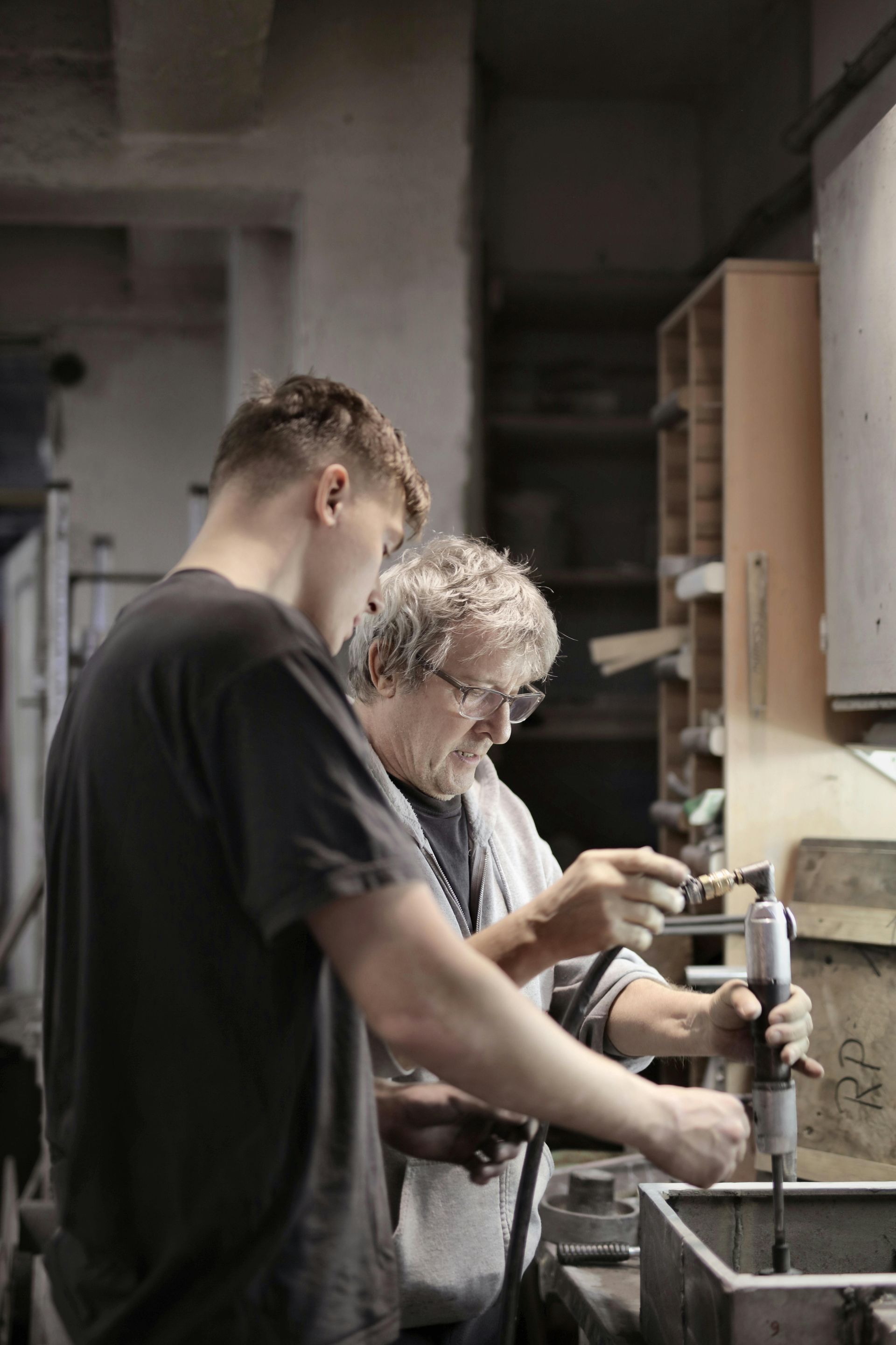 Two men working on machinery in a workshop. One man points, the other looks on.
