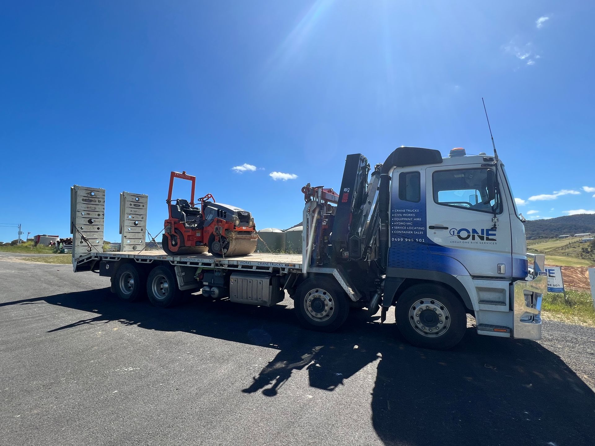 A Truck With a Tractor on the Back of It is Parked on the Side of the Road — One Group Industries Pty Ltd in Bathurst, NSW
