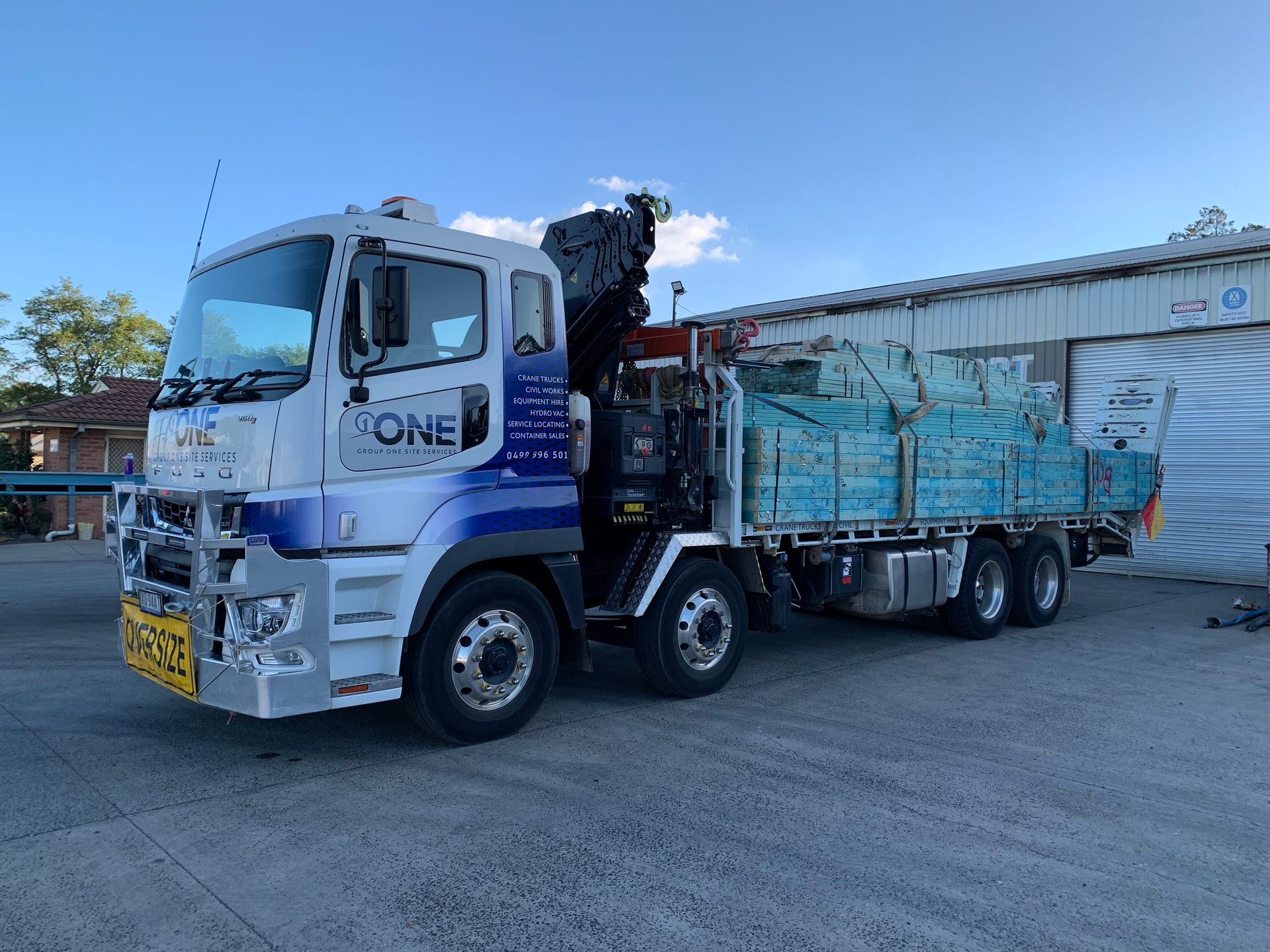 A Large Truck With a Crane on the Back is Parked in Front of a Building — One Group Industries Pty Ltd in Bathurst, NSW