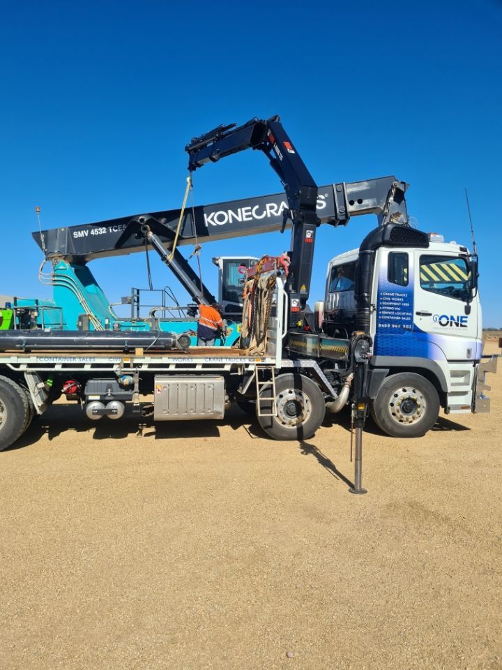 A Large Truck With a Crane on the Back is Parked in a Dirt Field — One Group Industries Pty Ltd in Bathurst, NSW