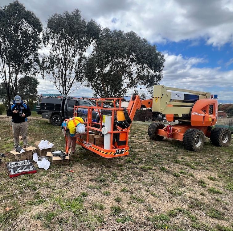 A Man is Standing Next to a Crane in a Field — One Group Industries Pty Ltd in Bathurst, NSW