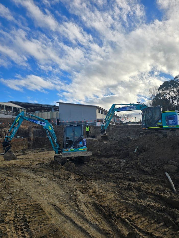 A Man is Digging a Hole Next to a Yanmar Excavator — One Group Industries Pty Ltd in Bathurst, NSW
