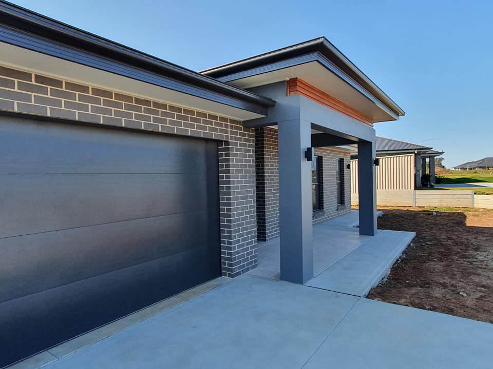 Modern brick home with gray garage door and entranceway, blue sky — One Group Industries Pty Ltd in Bathurst, NSW
