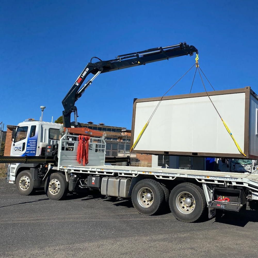 A Truck With a Crane Attached to It is Carrying a Container — One Group Industries Pty Ltd in Bathurst, NSW