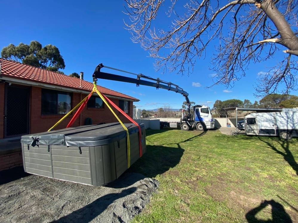 A Hot Tub is Being Lifted by a Crane in Front of a House — One Group Industries Pty Ltd in Bathurst, NSW