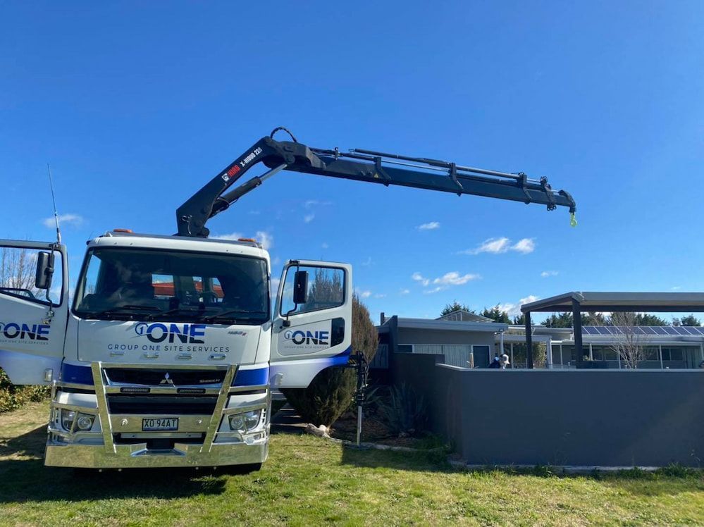 A Crane Truck is Parked in a Grassy Field Next to a House — One Group Industries Pty Ltd in Bathurst, NSW