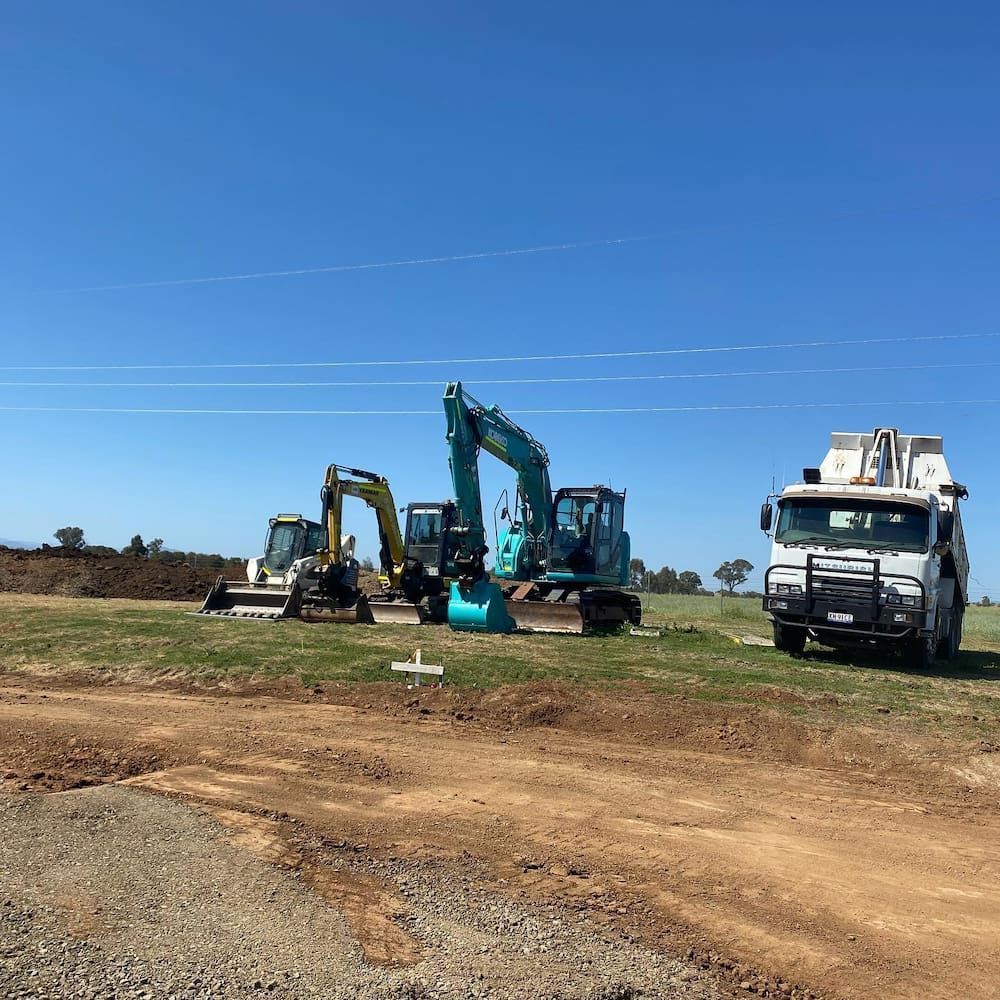 A Group of Construction Vehicles Are Parked in a Dirt Field — One Group Industries Pty Ltd in Bathurst, NSW