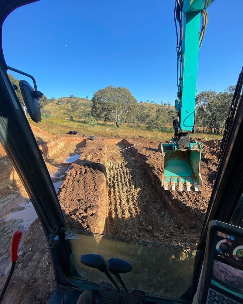 A Person is Driving an Excavator on a Dirt Road — One Group Industries Pty Ltd in Bathurst, NSW