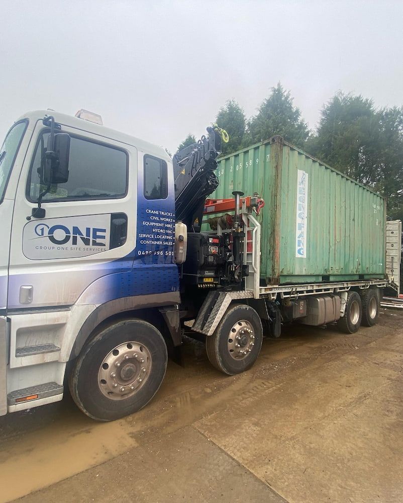 A Truck is Carrying a Green Shipping Container on the Back of It — One Group Industries Pty Ltd in Bathurst, NSW