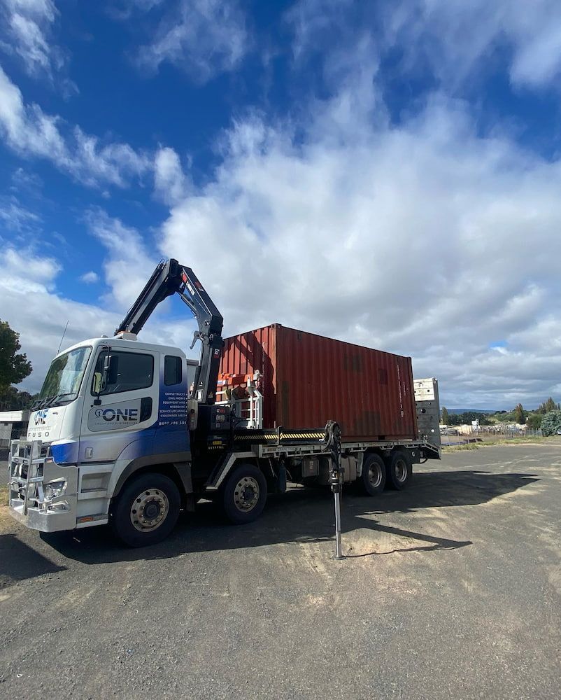 A Truck is Carrying a Red Shipping Container in a Parking Lot — One Group Industries Pty Ltd in Bathurst, NSW