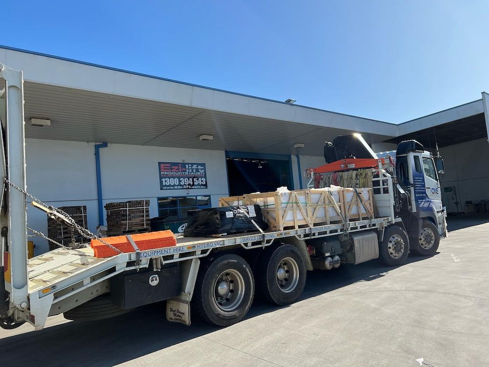 A Flatbed Truck With a Crane on the Back is Parked in Front of a Building — One Group Industries Pty Ltd in Bathurst, NSW