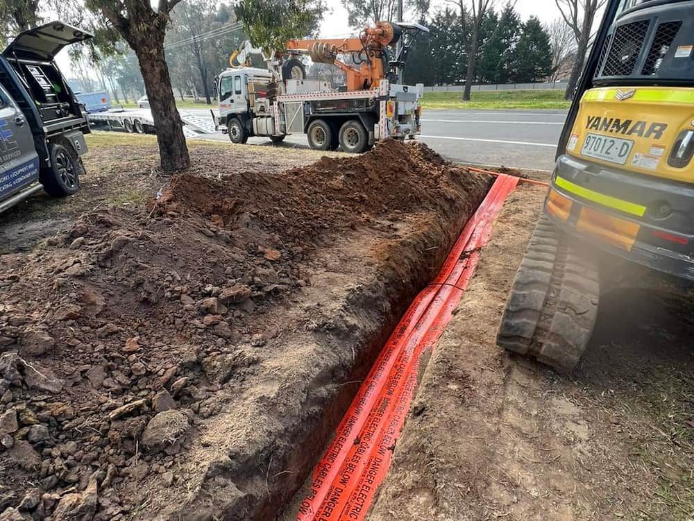 A Truck is Digging a Hole in the Ground Next to a Car — One Group Industries Pty Ltd in Bathurst, NSW