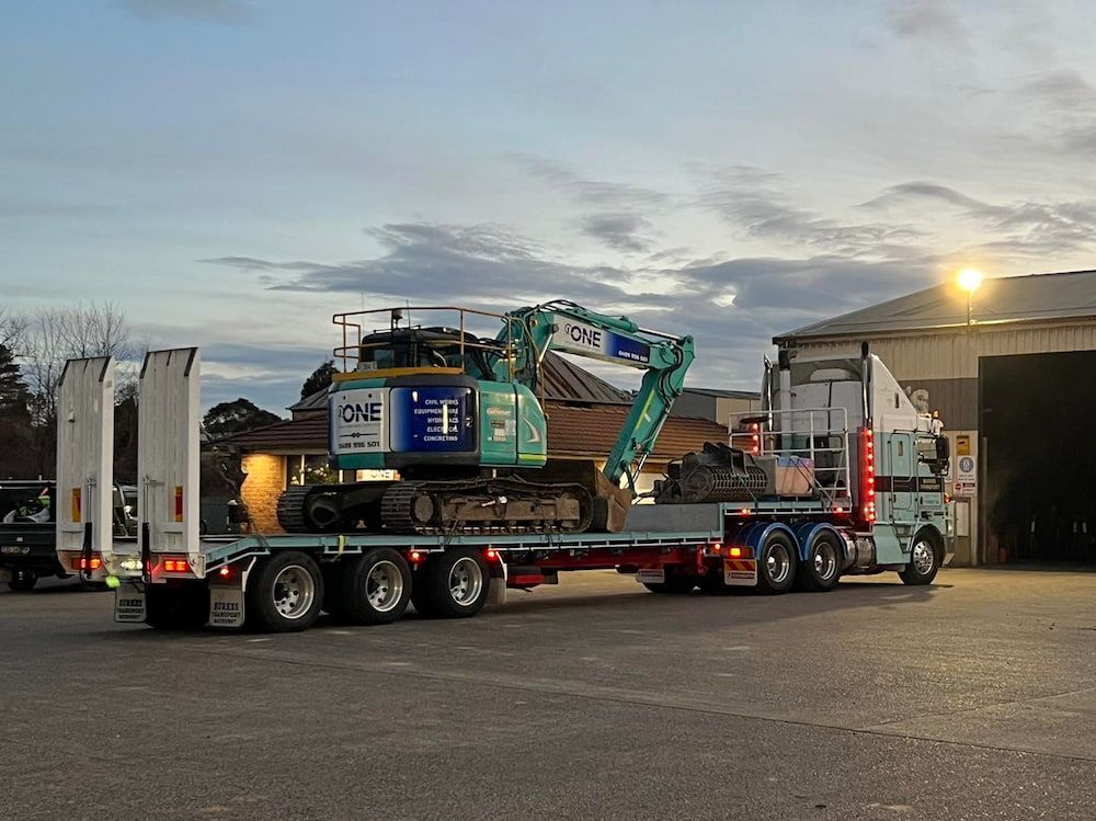 A Truck is Carrying a Large Excavator on a Flatbed Trailer — One Group Industries Pty Ltd in Bathurst, NSW