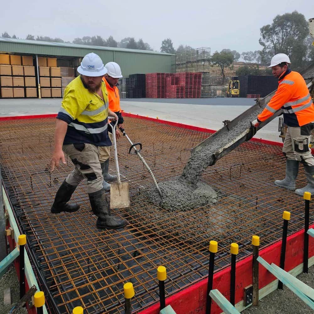A Group of Construction Workers Are Pouring Concrete Into a Foundation — One Group Industries Pty Ltd in Bathurst, NSW