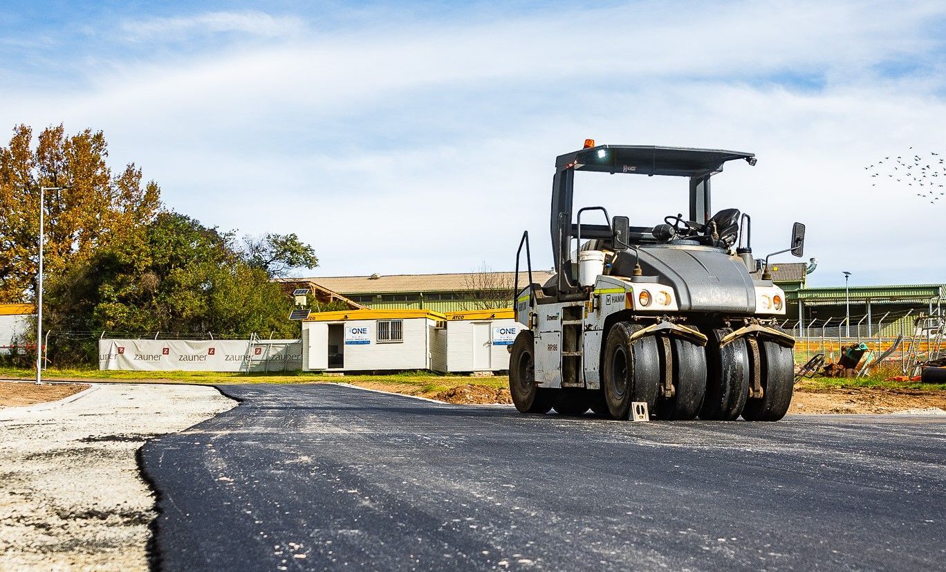 A Pneumatic Tire Roller Compacts Fresh Black Asphalt on A Road — One Group Industries Pty Ltd in Bathurst, NSW