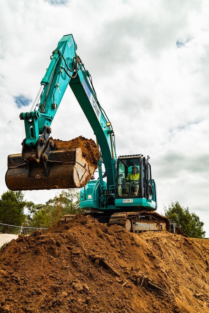 An Excavator is Loading Dirt Into a Bucket on Top of a Pile of Dirt — One Group Industries Pty Ltd in Bathurst, NSW