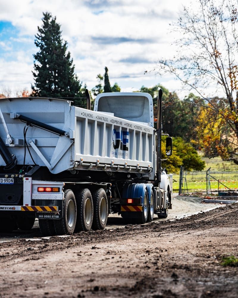 A Dump Truck is Driving Down a Dirt Road — One Group Industries Pty Ltd in Bathurst, NSW