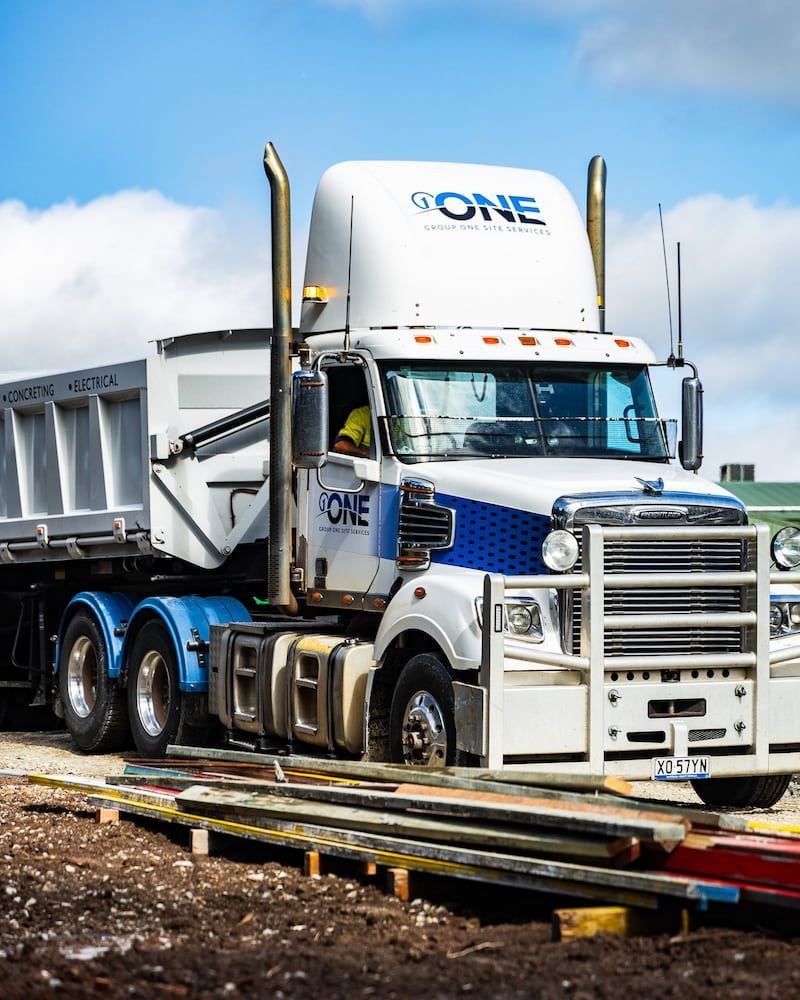 A Dump Truck With the Word One on the Side is Parked on a Dirt Road — One Group Industries Pty Ltd in Bathurst, NSW