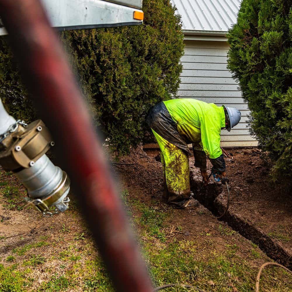 A Man is Digging a Hole in the Ground in Front of a House — One Group Industries Pty Ltd in Bathurst, NSW