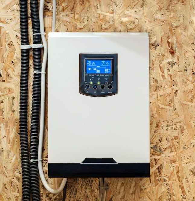 White solar power inverter with a blue display screen mounted on a wooden wall — One Group Industries Pty Ltd in Bathurst, NSW