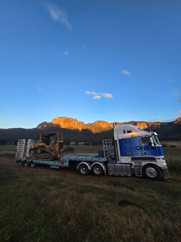 A Truck Carrying a Bulldozer on A Flatbed Trailer — One Group Industries Pty Ltd in Bathurst, NSW