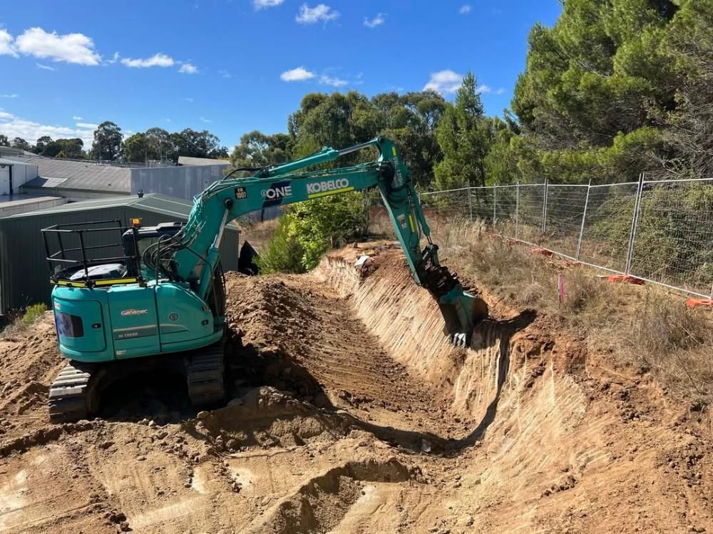 A Green Excavator is Digging a Hole in the Dirt — One Group Industries Pty Ltd in Bathurst, NSW