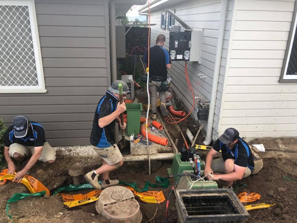 A Group of Men Are Working on a Septic Tank Outside of a House — One Group Industries Pty Ltd in Bathurst, NSW