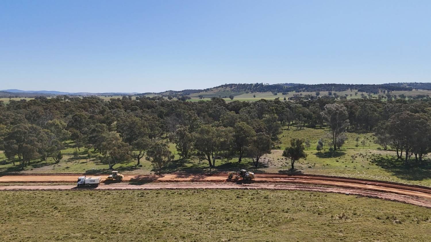 A Dirt Road Cuts Through a Grassy Field with Trees — One Group Industries Pty Ltd in Bathurst, NSW