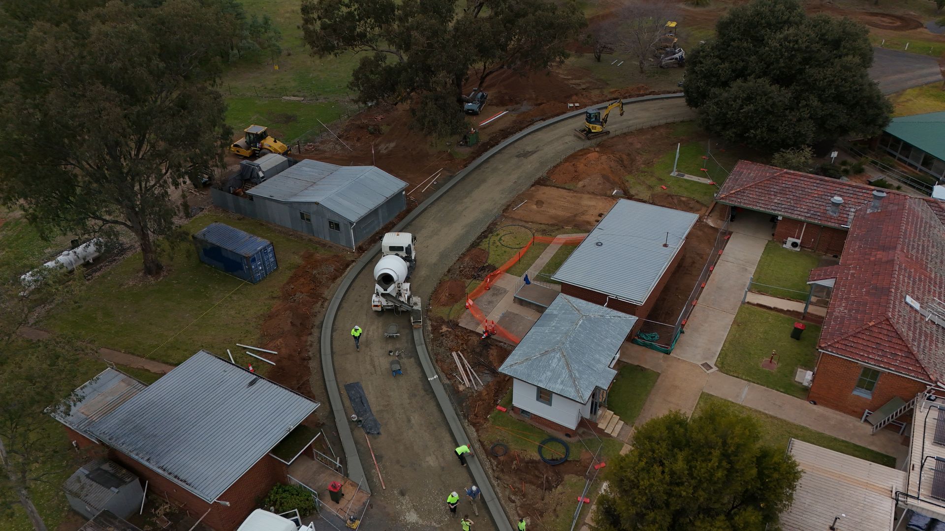 Aerial view of the Construction of a road near buildings and a cement truck with workers in yellow vests nearby — One Group Industries Pty Ltd in Bathurst, NSW