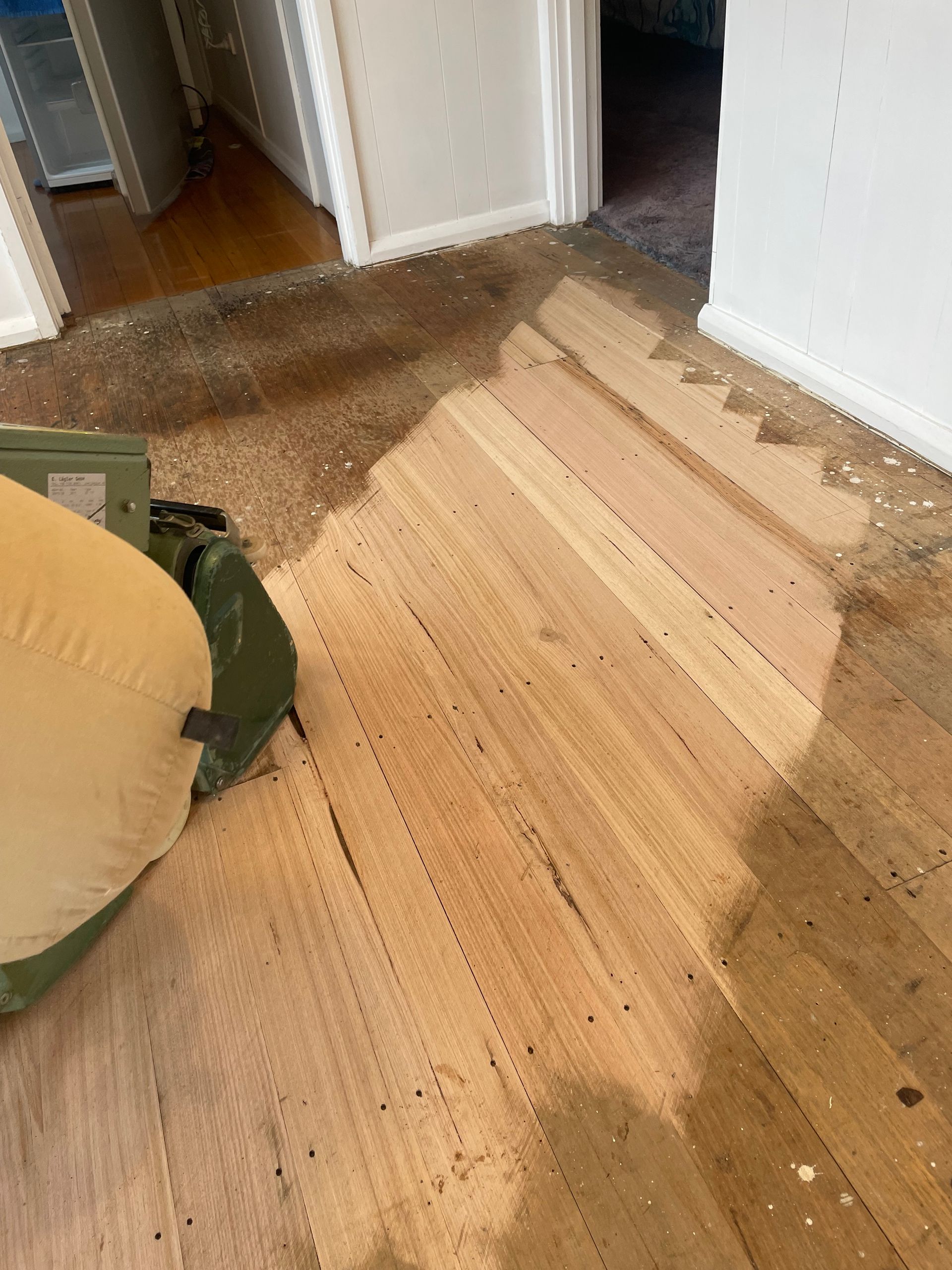 A floor sander machine strips old finish from a section of wood flooring in a room under renovation— Finer Floors In Warrane, TAS