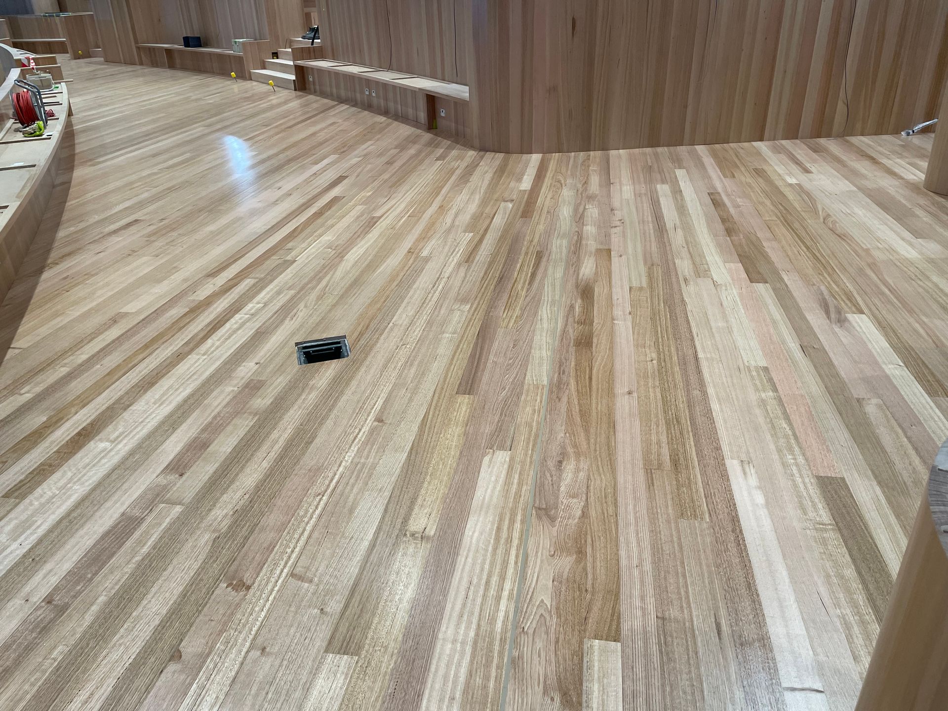 Curved wood floor in a modern room with a small black object on the floor — Finer Floors In Cambridge, TAS