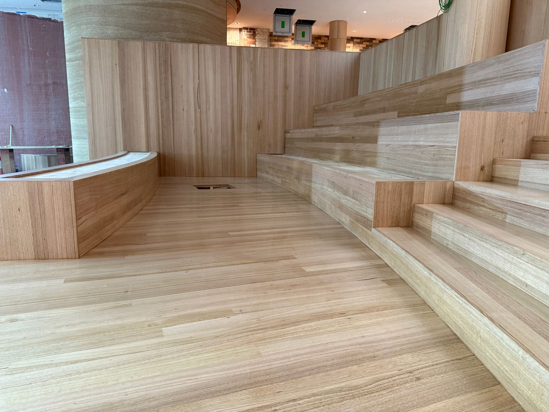 Wood-paneled interior with curved seating, wide floor, and stepped wooden platforms — Finer Floors In Cambridge, TAS